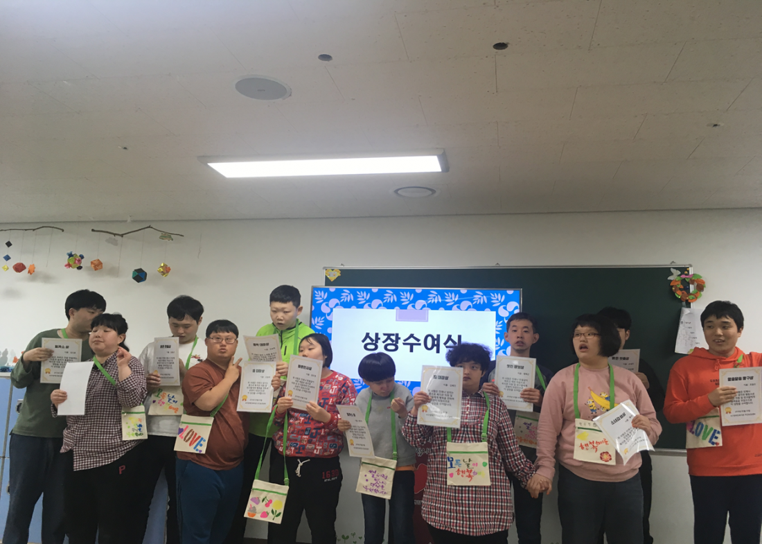 주간보호센터 이용자들이 어린이 날을 맞이하여 상장을 들고 서 있는 모습