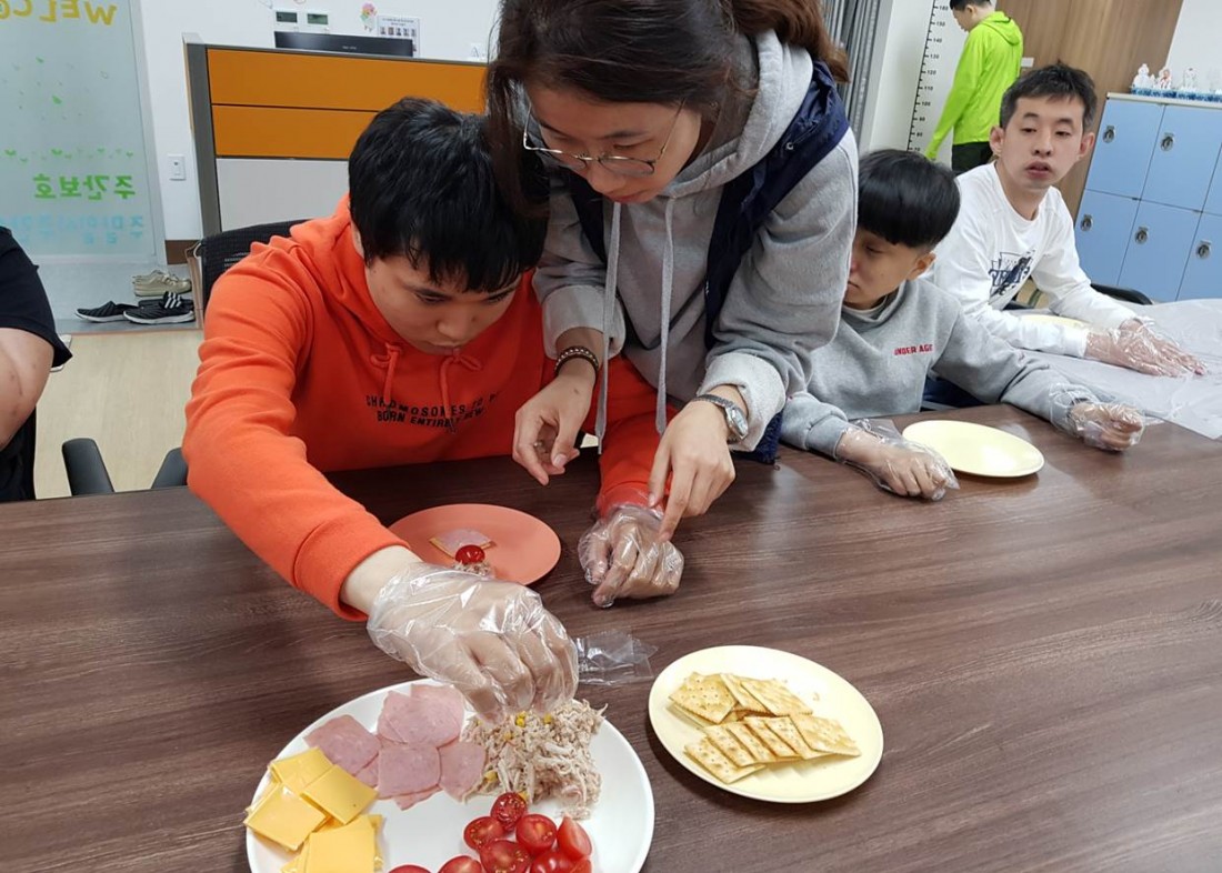 주간보호센터 이용자가 카나페 재료를 올리기 위해 재료를 쥐는 모습