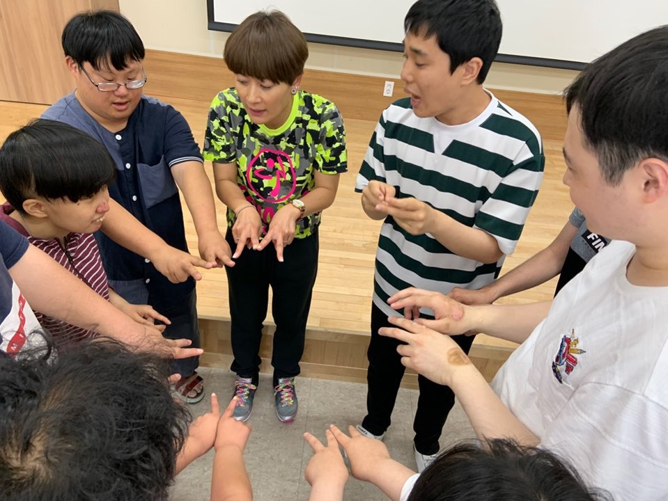주간보호센터 이용자들이 둥글게 서서 손가락을 모으고 있는 모습