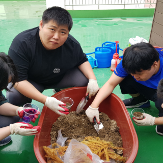 주간보호센터 이용자들이 화분을 만들기 위해 삽을 이용하여 흙을 담고 있는 사진