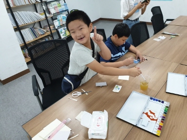 여름방학에 참여한 아이들이 밝게 웃으며 미술활동에 참여하는 모습