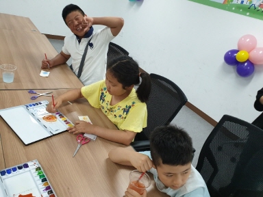 여름방학에 참여한 아이들이 밝게 웃으며 미술활동에 참여하는 모습
