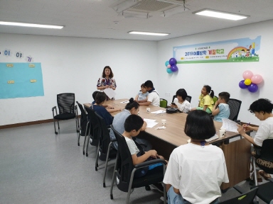 2019 여름방학 계절학교에 참여하기 위해 부모님과 아동들이 한 곳에 모여 사무국장님의 인사말을 듣고 있는 모습
