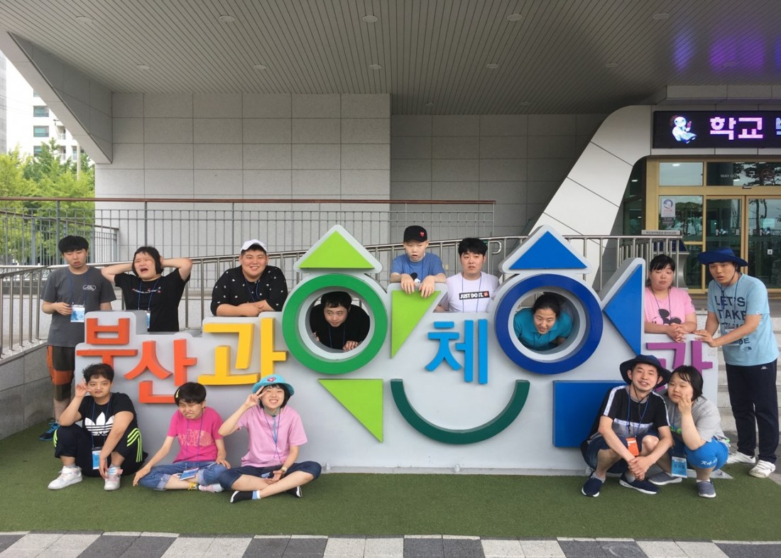 주간보호센터 이용자들이 부산과학체험관 입구에 위치한 조형물에 모여 찍은 기념사진