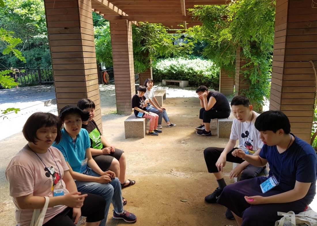 주간보호센터 이용자들이 각자 벤치에 앉아 휴식을 취하고 있는 모습