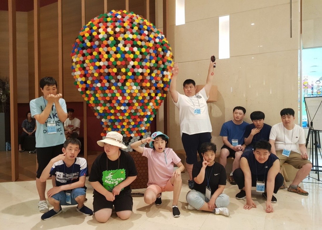 주간보호센터 이용자들이 롯데백화점 내부에 위치한 조형물에 모여 각자 포즈를 취하고 있는 사진