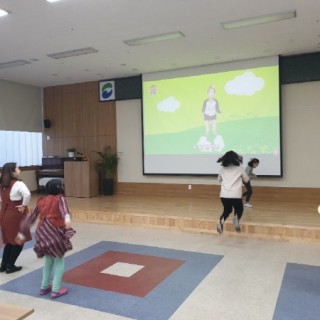 무용교실 참여아동들이 스크린에 나오고 있는 영상을 보고 이리저리 뛰어다니는 모습