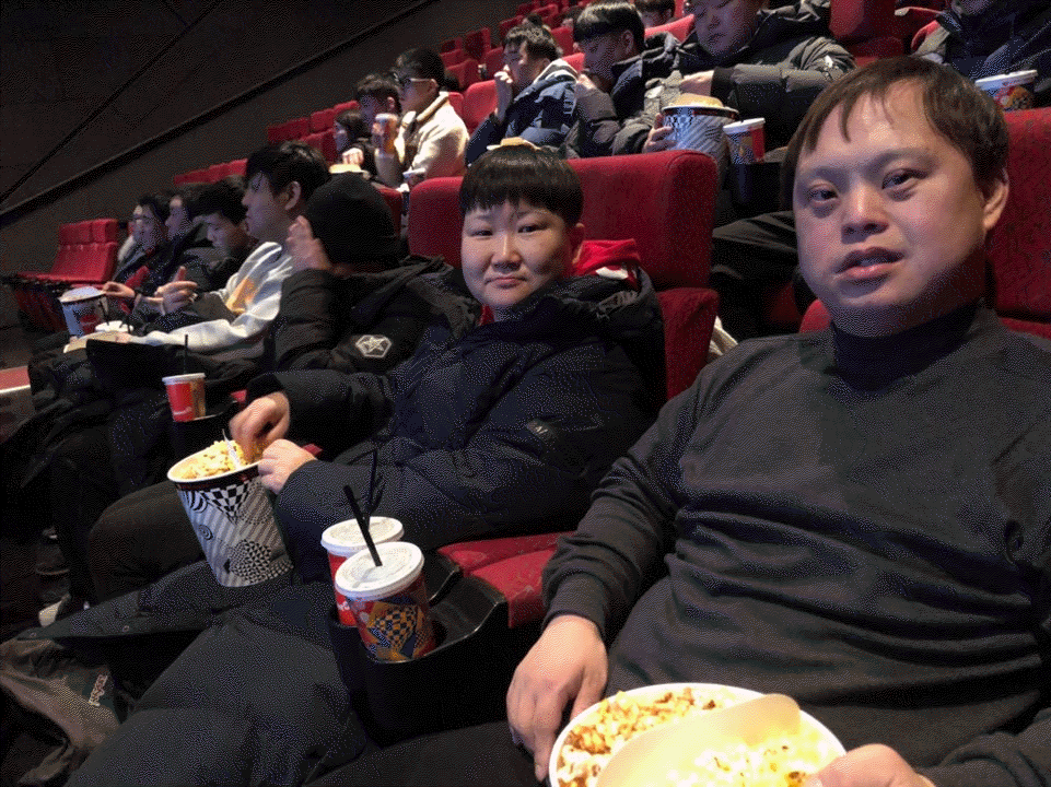 영화관 의자에 앉아 팝콘과 음료를 들고 있는 모습