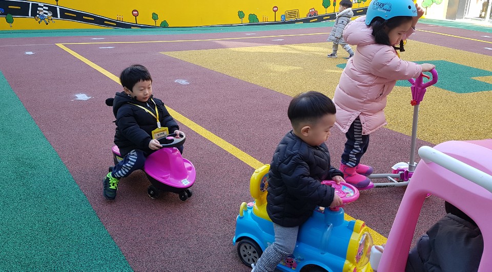 교통안전교육에 참여한 어린이들이 킥보드와 모형 자동차를 타고 모형 도로를 다니고 있는 모습