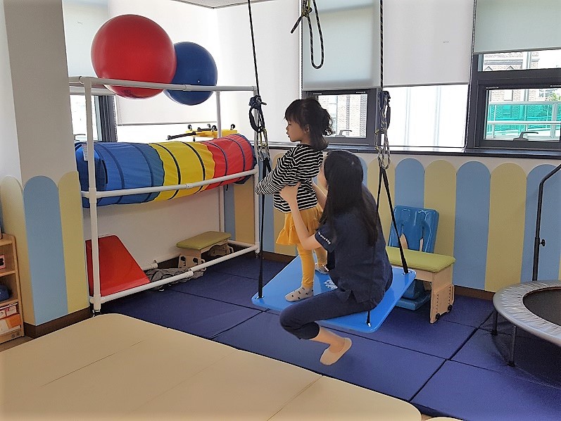 담당치료사가 아동의 균형감각을 위해 치료를 진행하는 모습