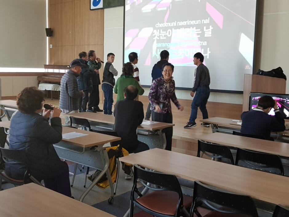 이용자들이 모여 마이크를 잡고 노래를 부르고 있고, 무대에서는 이용자들이 춤을 추고 있다.