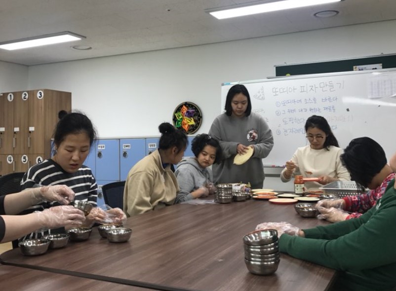 이용자들이 손에 비닐장갑을 끼고 피자만들기 체험을 하고 있는 모습