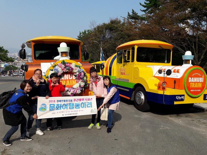 주간활동서비스 이용자들이 태종대다누비열차 앞에서 현수막을 들고 찍은 기념사진