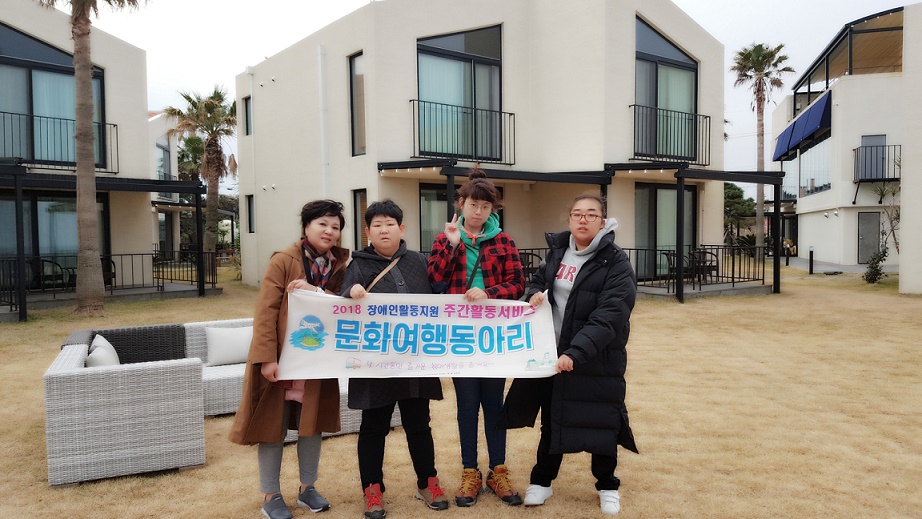 주간활동서비스 이용자들이 담당직원과 함께 현수막을 들고 숙소앞에서 찍은 사진