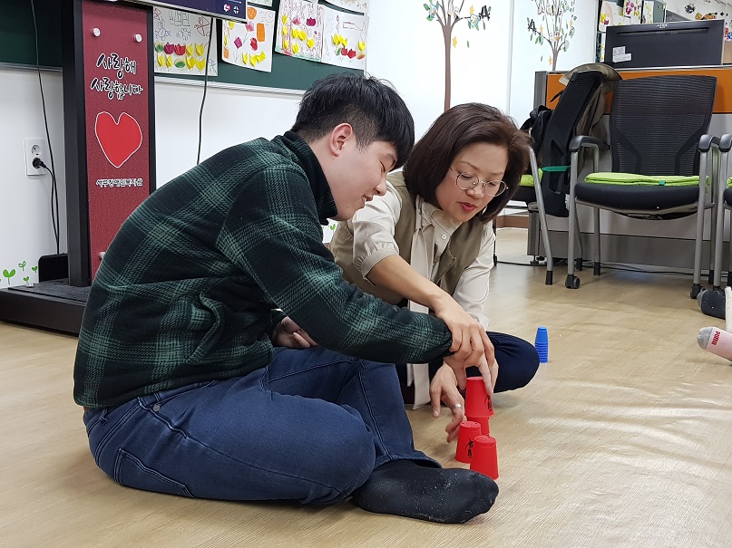 주간보호센터 이용자가 컵쌓기 게임을 하고있는 모습