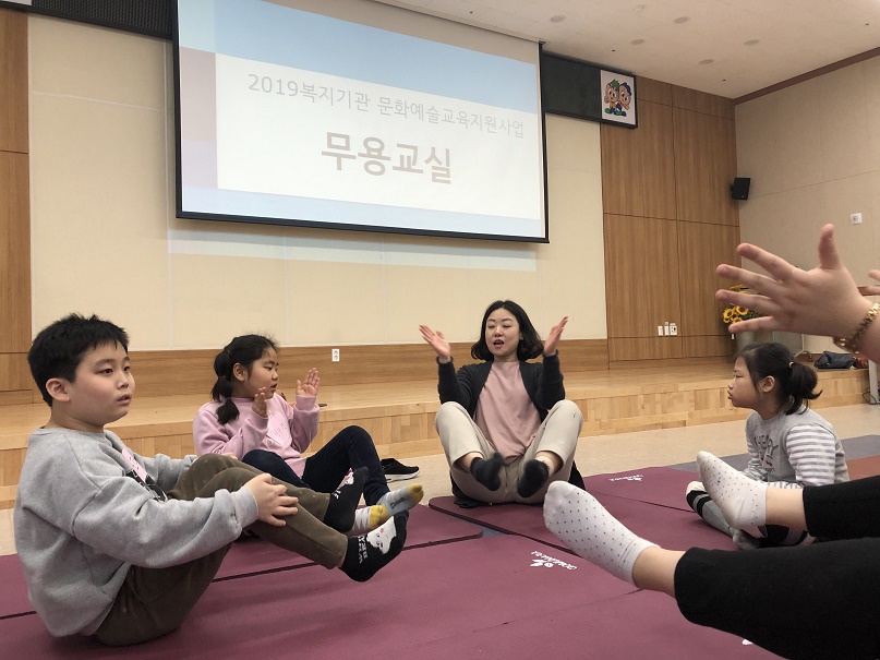 무용교실 강사가 참여아동들과 함께 다리를 들어올리며 활동을 진행하는 모습