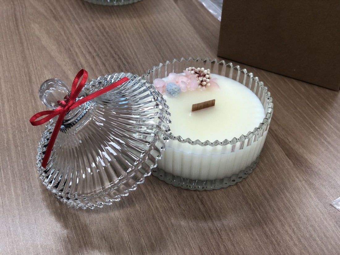 완성된 캔들의 모습 꽃잎이 올려져 있고 뚜껑에는 리본이 묶여있다.