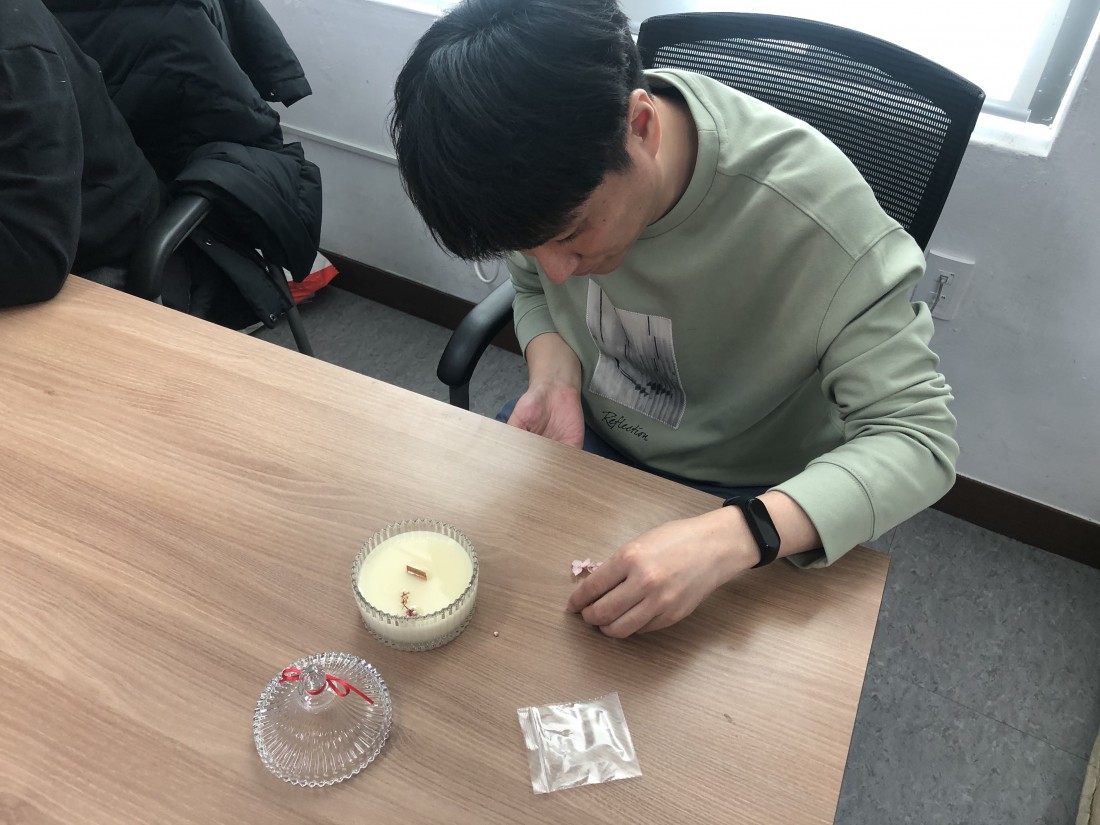 훈련생이 만들어진 캔들에 꽃잎을 올리고 있는 모습