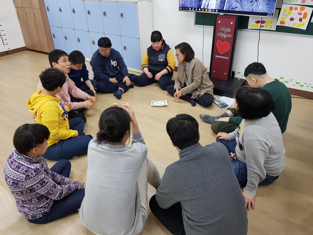 주간보호센터 이용자들이 둥글게 앉아 강사의 설명을 듣고 있는 모습