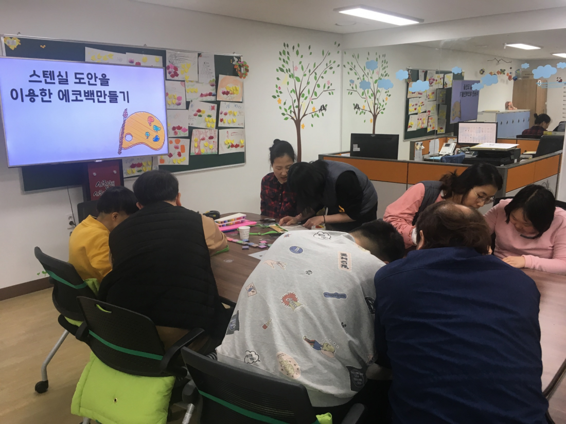 주간보호센터 이용자들이 책상에 앉아 에코백만들기 활동에 열중하고 있는 모습