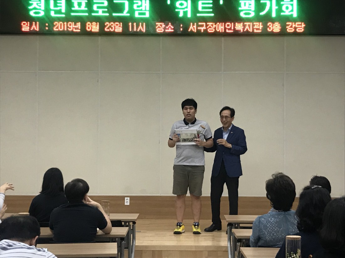 위트 프로그램의 한 참여자가 무대에 올라 긴장한 듯 굳은 표정으로 서있는 모습