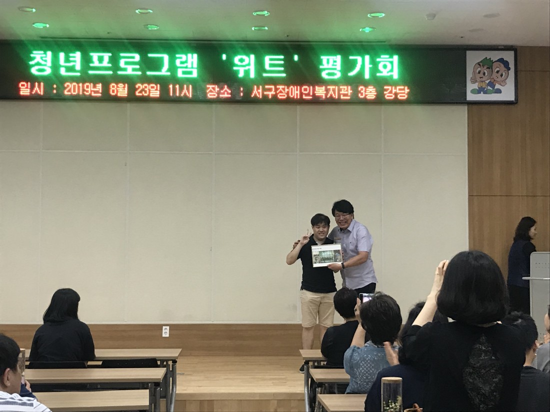 한 참여자가 그간 활동의 추억이 담긴 사진을 받아들고 정면을 향해 밝게 웃고 있는 사진