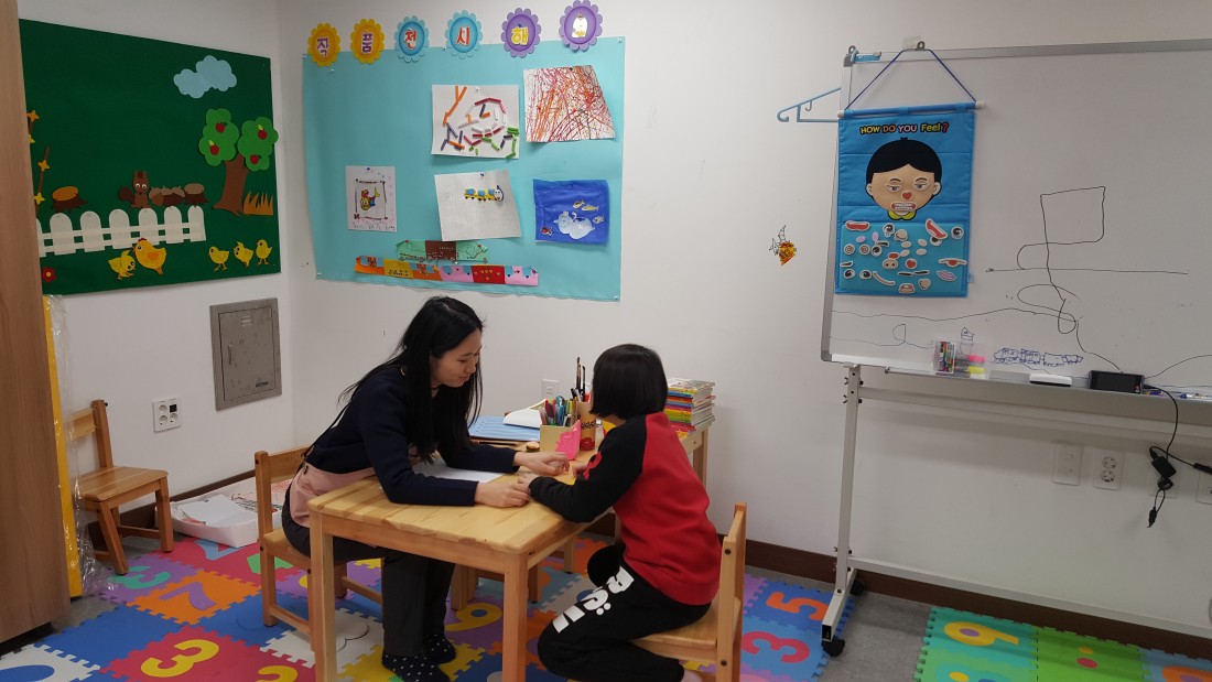 미술치료사가 치료아동이 그림 그림을 보고 있는 모습