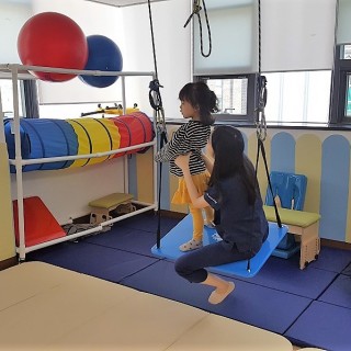 담당치료사가 아동의 균형감각을 위해 치료를 진행하는 모습