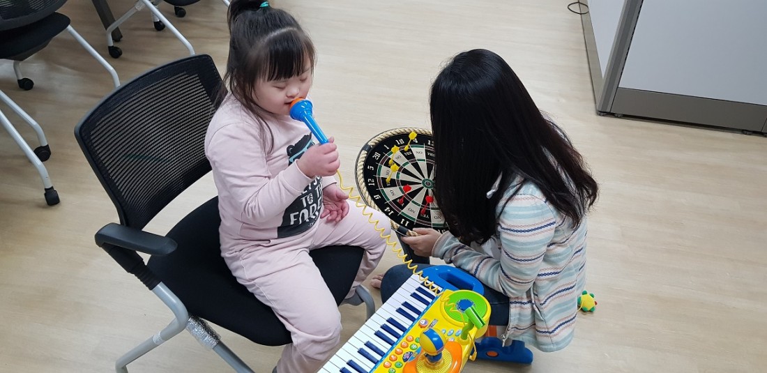 아동이 장난감 마이크를 만지며 노래를 부르는 듯한 모습을 보이고 있다.