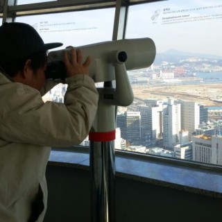 훈련생이 부산타워에서 망원경을 통해 바깥을 보고 있다.