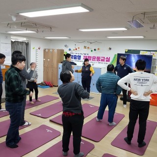 주간보호센터 이용자들이 요가매트위에 서서 강사를 바라보고 있는 모습