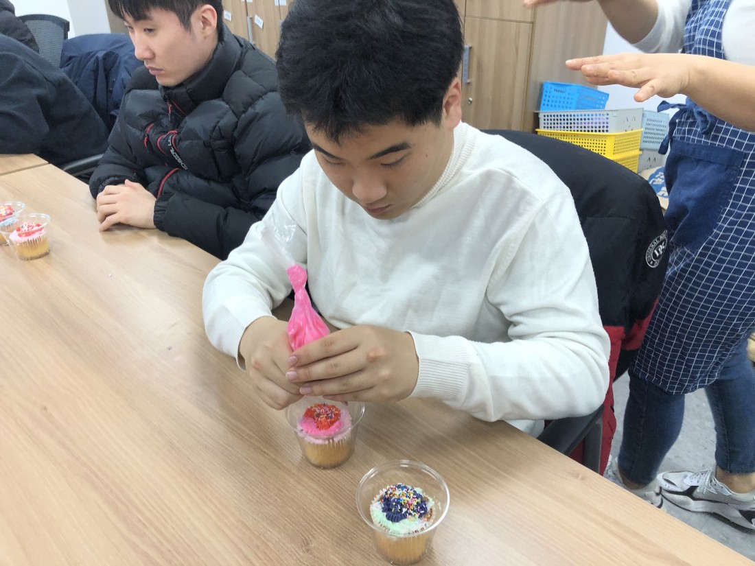 훈련생이 분홍색 크림을 이용하여 빵위에 그림을 그리고 있는 모습